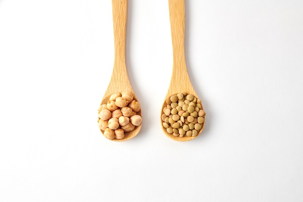 Top view shot of dried lentils, chickpeas with wooden spoons isolated on white background