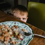 grumpy toddler child refusing to eat plate of food
