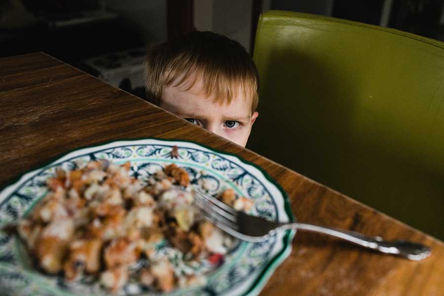 grumpy toddler child refusing to eat plate of food
